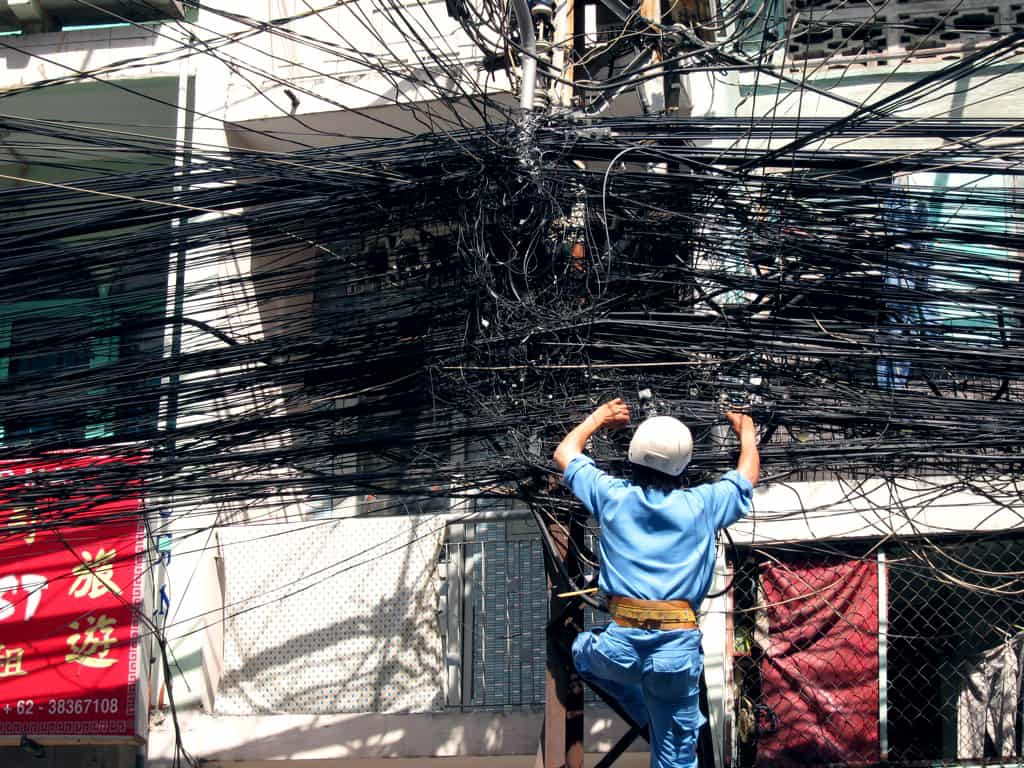 man working on mass of telecommunication wires